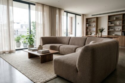 Canapé panoramique en bouclé taupe au centre d'un salon contemporain avec sol en béton poli et grandes fenêtres