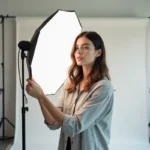 Photographe en studio réglant un réflecteur blanc froid pour un portrait professionnel en lumière blanche naturelle