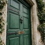 Porte d'entrée en bois vert forêt avec quincaillerie en fonte sur façade en pierre de maison de campagne française